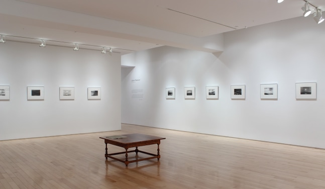 Photograph of showing a corner view of an exhibition space, with ten drawings hanging on white walls.