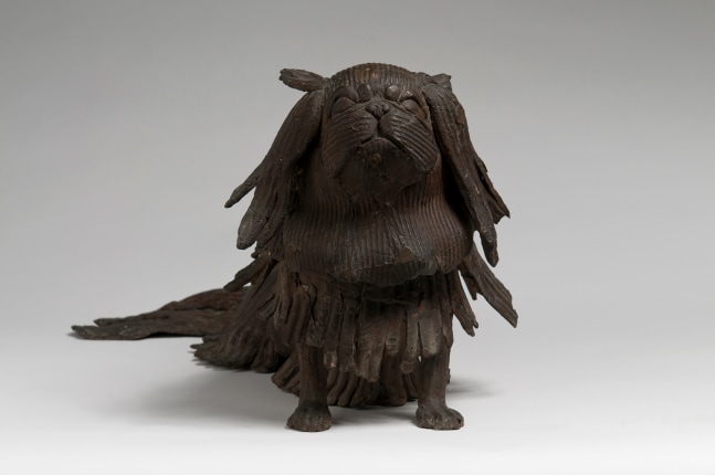 Front view of a bronze sculpture of a small, shaggy dog