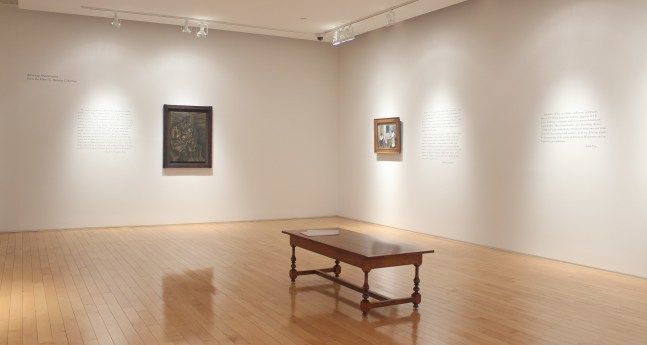 Photograph showing a corner view of an exhibition space, with two paintings hanging on white walls
