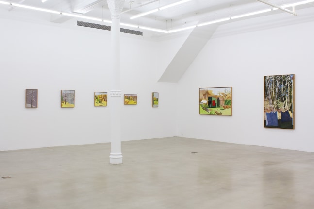 Photograph showing a corner view of an exhibition space, with seven paintings hanging on white walls