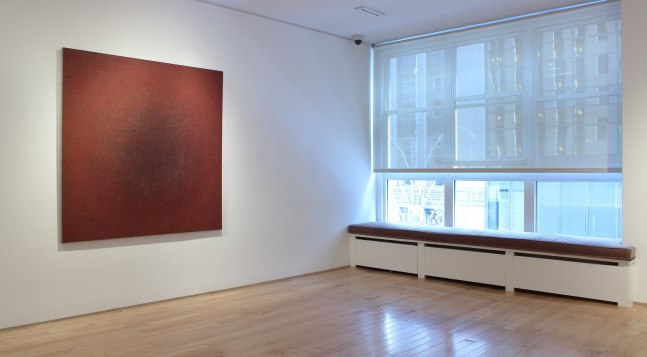 Photograph showing a view of an exhibition space, with a large painting hanging on a white wall