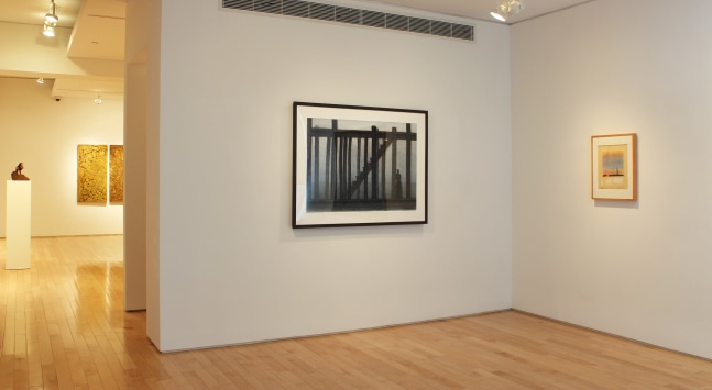 Photograph showing a corner view of an exhibition space, with two framed drawings hanging on the white walls