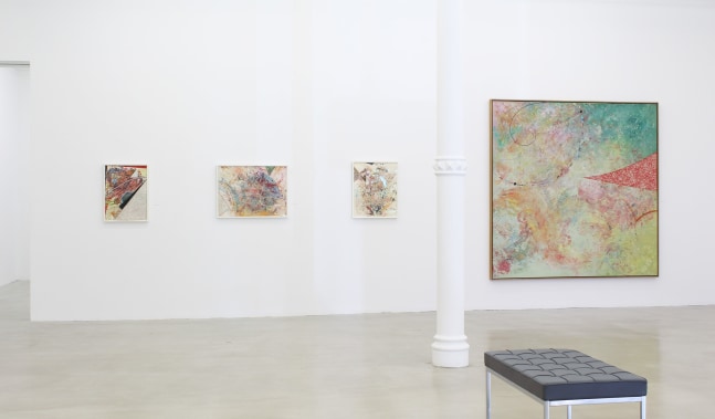 Photograph showing a view of an exhibition space, with four paintings hanging on a white wall