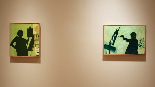 Photograph showing a view of an exhibition, with two small framed paintings hanging on a white wall