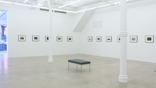 Photograph of eleven framed drawings in a white gallery exhibition space