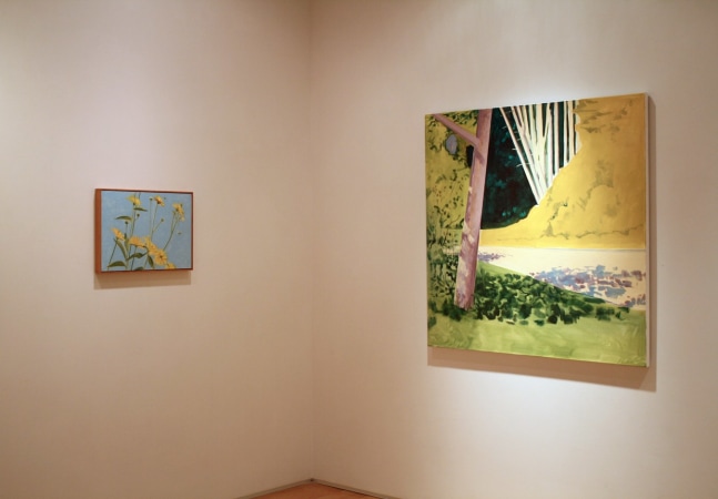 Photograph showing a corner view of an exhibition space, with two paintings hanging on white walls