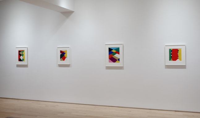 Photograph showing a view of an exhibition space, with four paintings hanging on a white wall