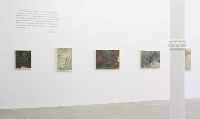 Photograph showing a view of an exhibition space, with five paintings hanging on a white wall