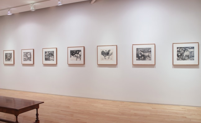 Photograph showing a view of an exhibition space, with seven framed drawings hanging on a white wall
