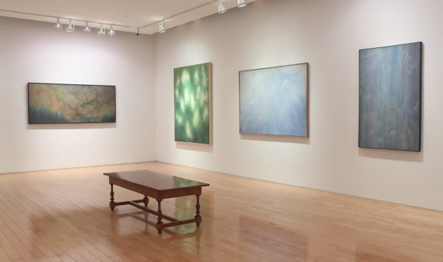 Photograph showing a view of an exhibition space, with four large paintings hanging on white walls