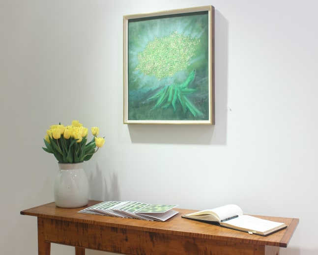 Photograph showing a view of an exhibition space with one painting hanging over a wooden table