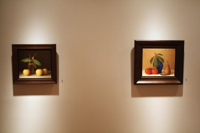 Photograph showing a view of an exhibition, with two small framed paintings hanging on a grey wall