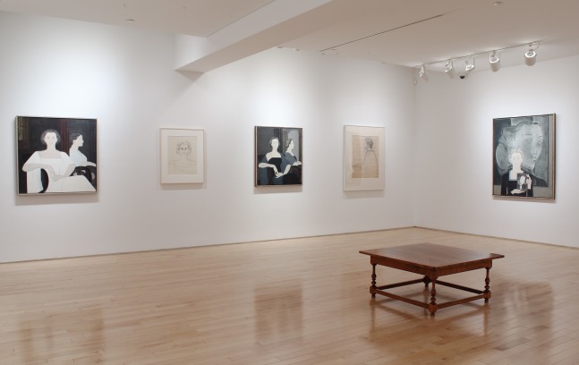 Photograph showing a corner view of an exhibition space, with five paintings hung on white walls