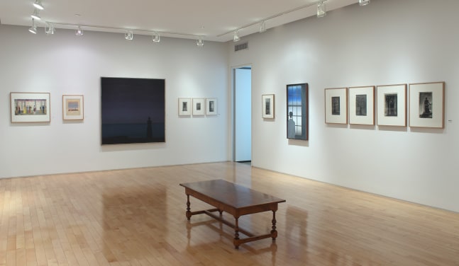 Photograph showing a corner view of an exhibition space, with two paintings and ten smaller framed drawings hanging on white walls