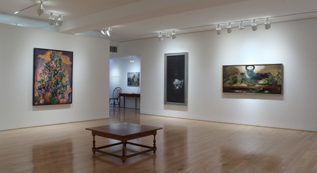 Photograph showing a corner view of an exhibition space with four paintings hanging on white walls