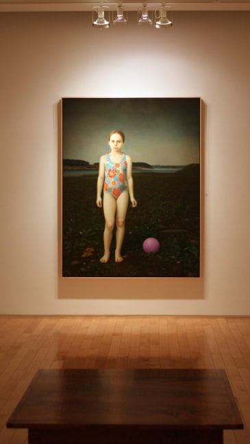 Photograph showing a view of an exhibition space, with one large framed painting hanging on a white wall