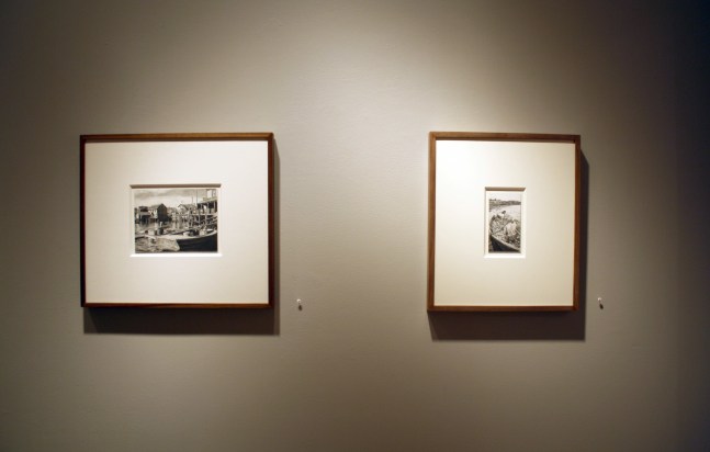 Photograph showing a view of an exhibition, with two small framed drawings hanging on a grey wall