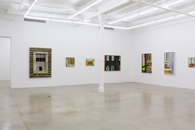 Photograph showing a corner view of an exhibition space, with seven paintings hanging on white walls