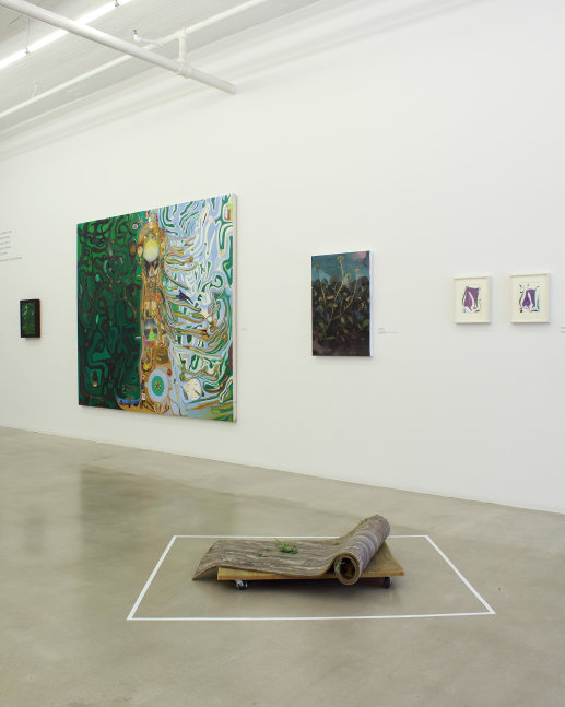 Photograph of a detail of an exhibition with five paintings hung on a white wall and a sculpture on the ground in front