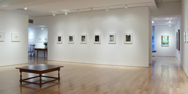 Photograph showing a corner view of an exhibition space, with ten framed drawings hanging on white walls