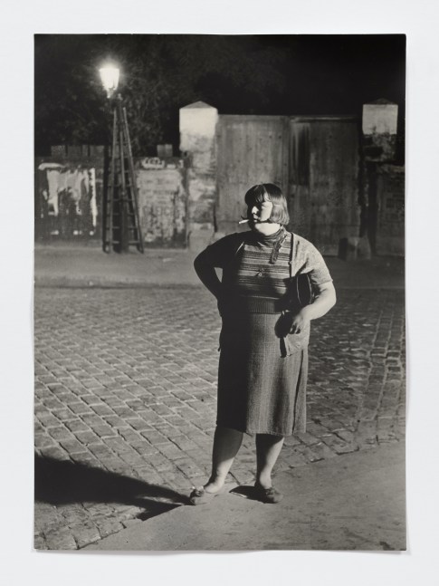 Black and white photographic portrait of woman smoking in the street.