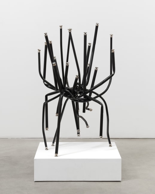A free standing sculpture by Josh Callaghan of black metal chair legs entangled and extending skyward.