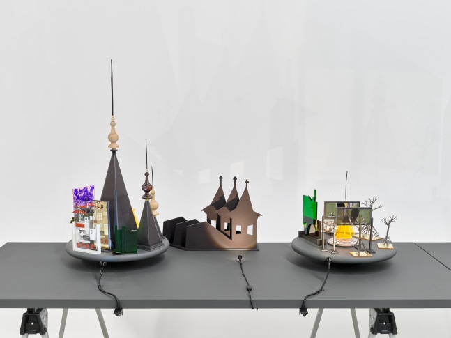 A series of assemblage sculptures comprised of upside down crystal vases, miniature trees, photographs printed on plexiglass and steeples made from styrene atop rotating platforms.