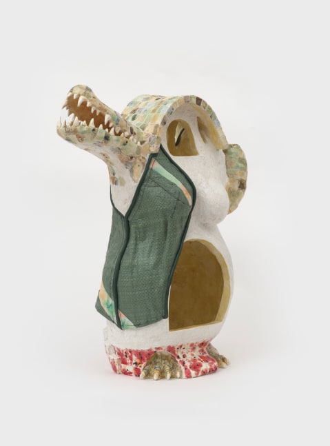 A ceramic sculpture with an alligator's face and a rounded body with an arched doorway to a cavity that connects to both sides of the sculpture.