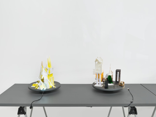 A series of assemblage sculptures comprised of upside down crystal vases, miniature street lamps, photographs printed on plexiglass and steeples made from styrene atop rotating platforms.