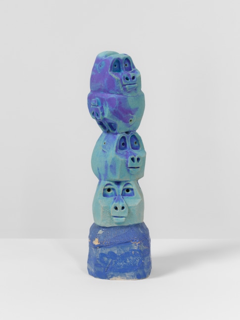 A ceramic sculpture by Brad Eberhard of blue monkey's heads stacked on top of each other.