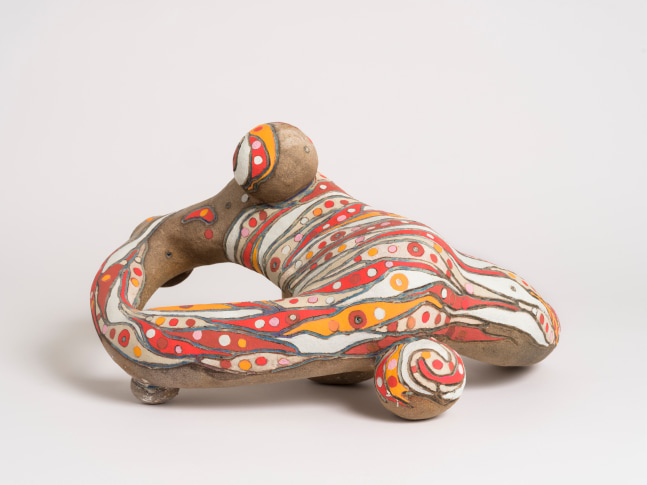 An abstract ceramic sculpture by Brad Eberhard with rounded shapes and a painted orange and red pattern.