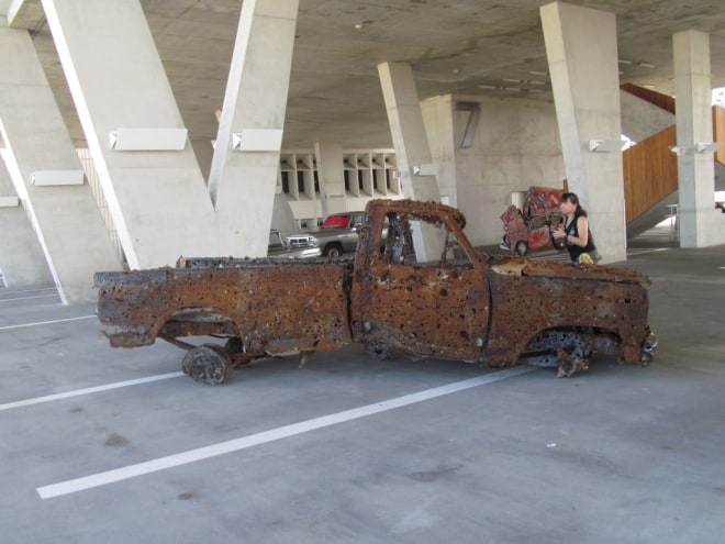 Here lies the remains of what used to be a truck, but what then became a target for an annual machine-gun festival in Kentucky. Now you know that type of festival exists. (Lucien Smith, &ldquo;The sound of the engine still running and for the last time they locked eyes, together again in the end,&rdquo; 2013.)