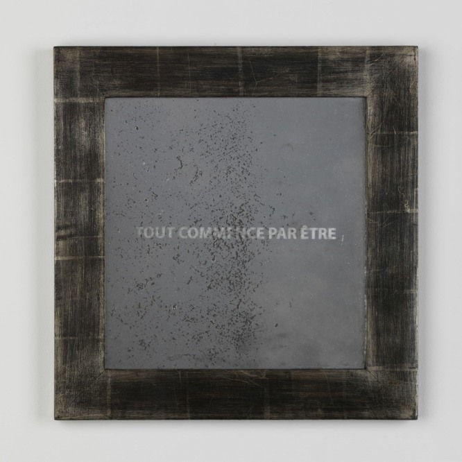 frame with the words 'tout commence par etre' written inside on a white wall