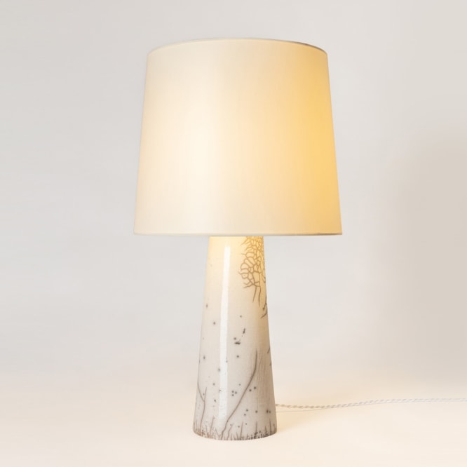 Raku lamp in a classic form with a white speckle and a white fabric shade. Light is illuminated 