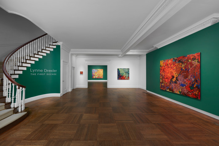 Dark green room with abstract bright colored paintings