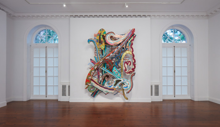 Large sculpture made of bright, swirling curves in a white room