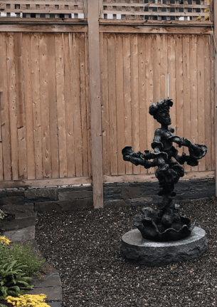 Garden setting for Yulla with Elaborate Head Piece sculpture by Yulla Lipchitz.