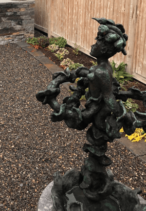 Garden setting for Yulla with Elaborate Head Piece sculpture by Yulla Lipchitz.