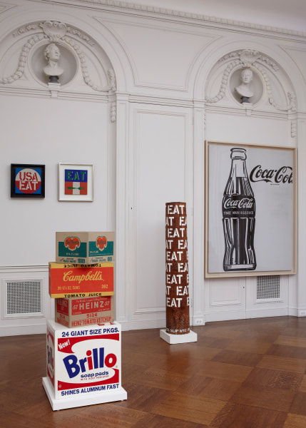 Installation view of The Pop Object: The Still Life Tradition in Pop Art at Acquavella Galleries, including Indiana's paintings USA Eat, Eat, and the the sculpture Column Eat