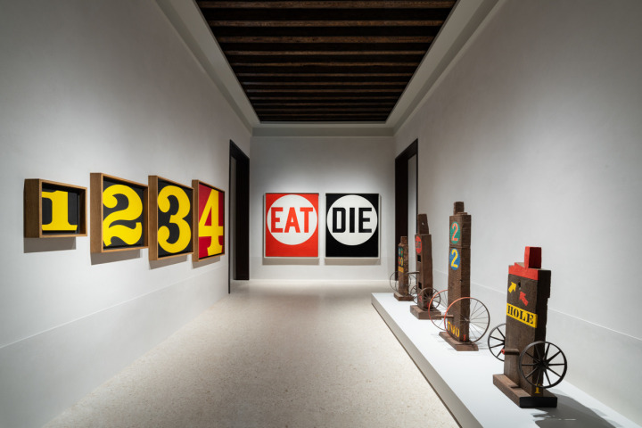 Installation view of Robert Indiana: The Sweet Mystery. Left to right: the painting Exploding Numbers, the painting Eat/Die, and four bronze sculptures