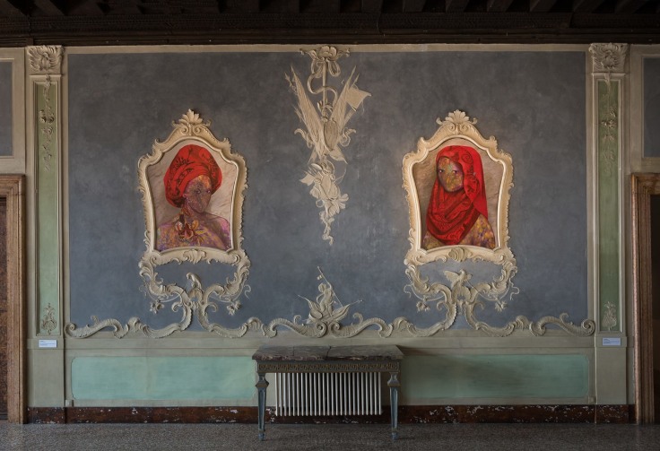 Wall insallation of two cosmically-colored figures with wearing a red turban and the other wearing a red hijab set in a gilded ivory frames by Firelei B&aacute;ez.