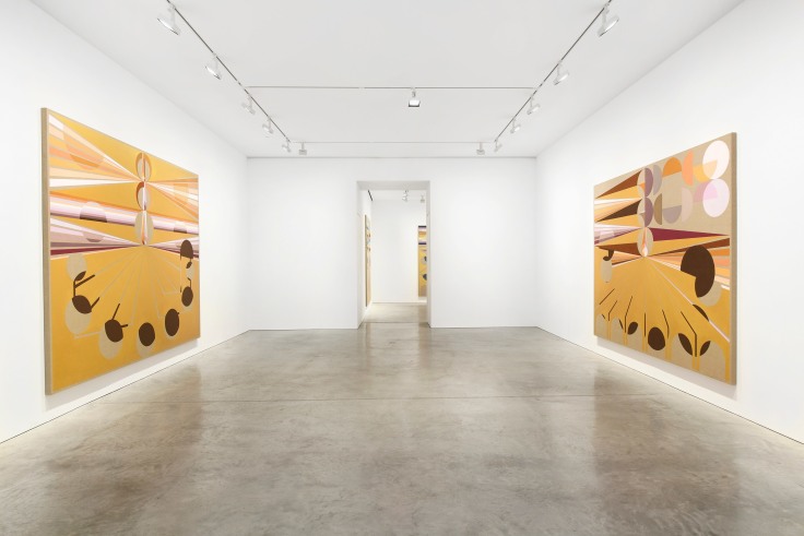 gallery with art with an entry way in the center leading to another room