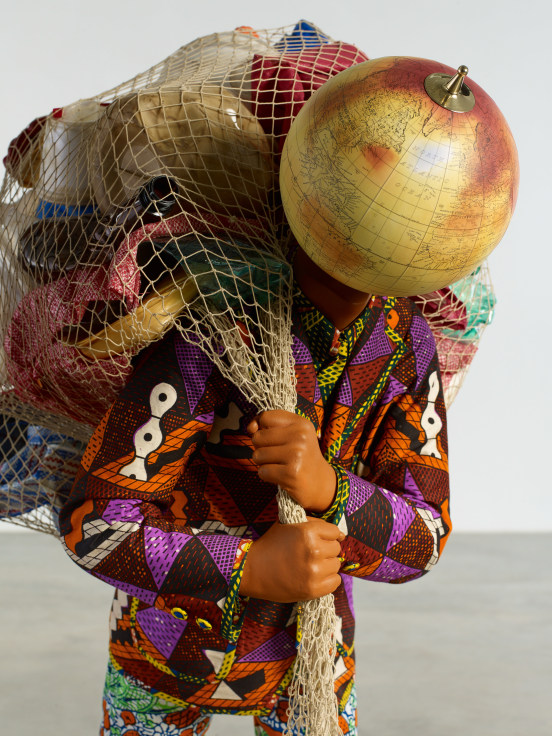 mannequin with a globe for a head holding a net full of belongings