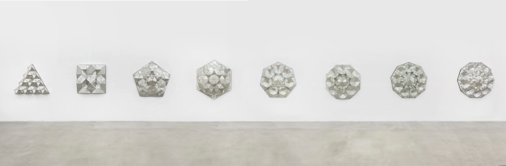 Eight geometric reverse glass sculptures mounted to the wall with painted details by Monir Shahroudy Farmanfarmaian.