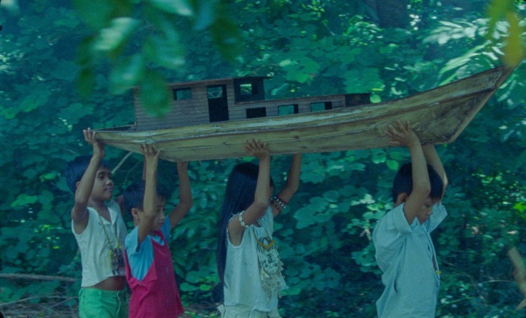Group of children carrying a wooden boat in a jungle