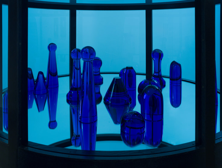 Close-up view of blue glass sculptures inside the blue cylindrical structure