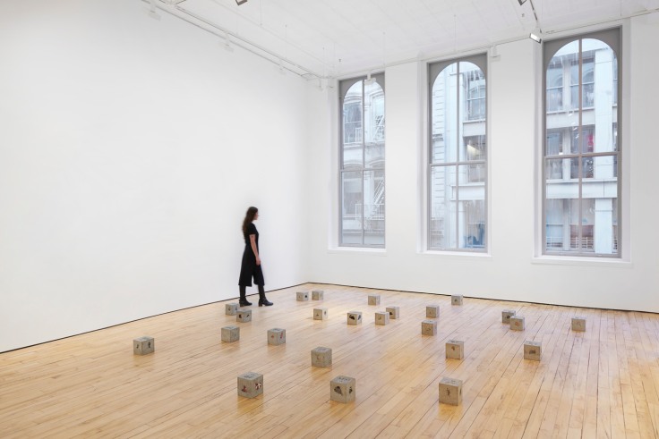 Cement blocks with T shirts casted inside scatter on gallery floor
