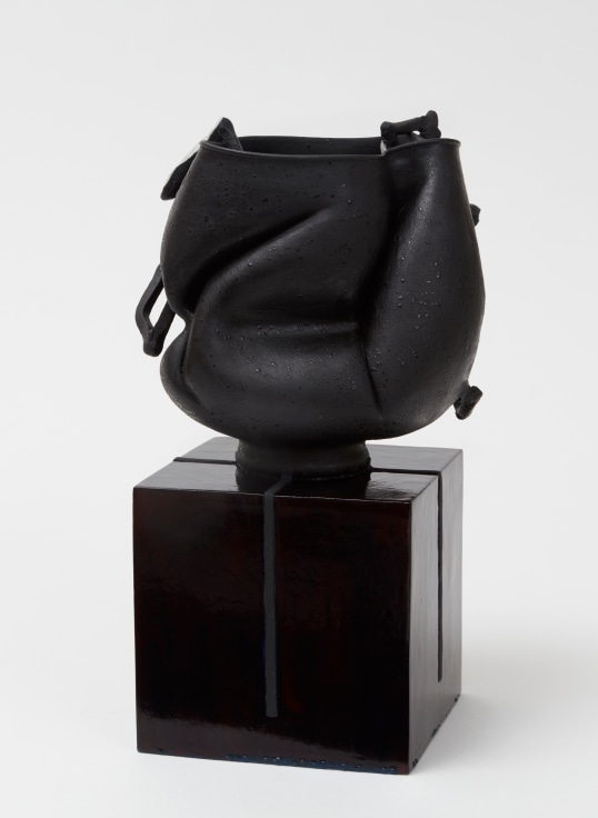 Sunken-in, jet-black porcelain pot with twisting handles jutting out by Kathy Butterly.