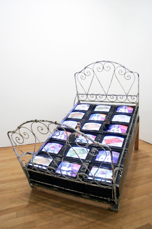 , NAM JUN PAIK,&nbsp;TV Bed, 1971/72, Three channel color video, eighteen TVs, antique metal bed frame, wood, puppets, 90 1/2 x 78 3/4 x 59 in. (230 x 200 x 150 cm)
