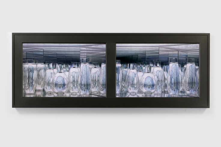 Handblown glass vases with reflective surfaces in two symmetrical lit spaces framed behind a walnut frame